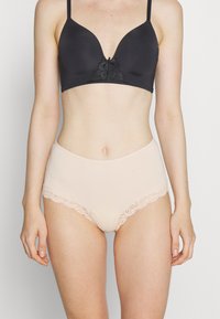 Black lace-trimmed bra with smooth cups and adjustable straps, paired with high-waisted nude panties featuring lace accents on the waistband.