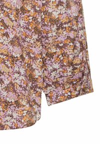 Blomsterpræget stof i nuancer af lilla, orange og creme med en blød tekstur. Designet har små blomster og en afslappet pasform.