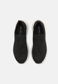 Black knitted sneakers with gold speckles, elasticized entry, and white rubber soles. Features a logo print on the insole.
