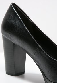 Escarpins noirs en cuir avec un talon carré texturé. Tige lisse avec un design à bout pointu.