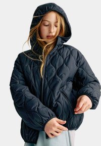 Czarna, pikowana kurtka puchowa z kapturem, z zamkiem błyskawicznym i bocznymi kieszeniami, widocznymi detalami szwów oraz miękkim, teksturowanym materiałem.