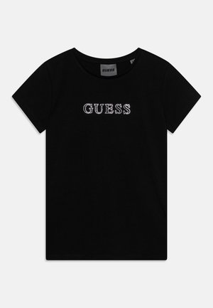 T-shirt de algodão preto com mangas curtas, apresentando um logótipo "GUESS" adornado com strass no centro, gola redonda e textura suave.