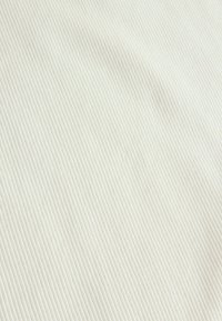 Textureret stof i off-white med fine vertikale striber, der skaber et ribbet mønster. Glat overflade, let i udseendet.
