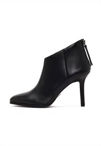 Bota de tobillo de cuero negro con punta afilada, alto tacón de aguja y cierre con cremallera lateral. Textura suave sin patrones ni acentos.