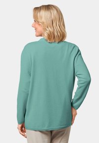 Türkiser Strickpullover mit langen Ärmeln, Rundhalsausschnitt und lockerer Passform. Weiche Textur mit gerippten Bündchen und Saum.