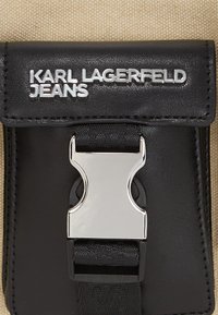 Black leather wallet with a silver metal clasp. Features the embossed text "KARL LAGERFELD JEANS" above the clasp, showcasing a sleek design.