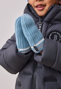 Knitane svetlo modre rokavice s teksturirano tkanino in belimi ter sivimi črtami blizu manšet, ki jih drži oseba v puhovki.