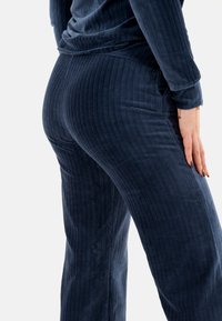 Pantalones de canalé de color azul oscuro con un acabado texturizado, que presentan un diseño de pierna recta y una cinturilla elástica.