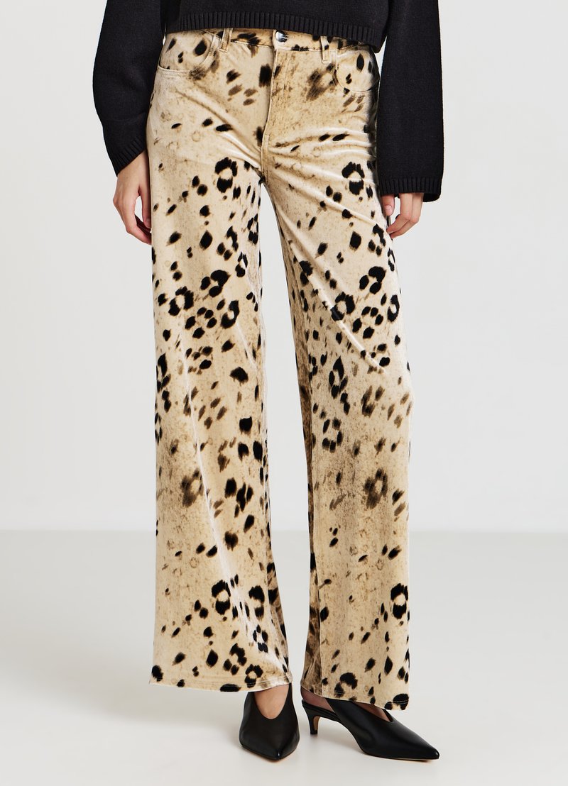 Beige Samt-Hose mit weitem Bein und schwarzem Leopardenmuster. Verfügt über eine hohe Taille und Fronttaschen, kombiniert mit spitzen schwarzen High Heels.