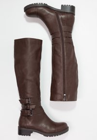 Botas de cuero sintético marrón hasta la rodilla con un eje estructurado, acentos de doble hebilla, cremallera lateral y suela de goma texturizada.