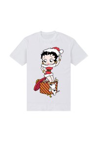 Hvid T-shirt med en tegneseriefigur i rødt og hvidt tøj, stående på en stribet gaveæske med en lille hund.