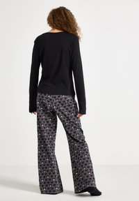 Sort langærmet top parret med grå pyjamasbukser med hjerte- og kaninprint. Blødt stof med afslappet design og brede ben.