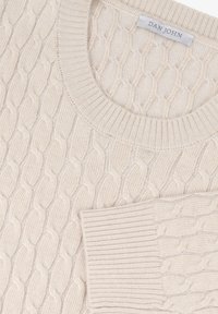 Suéter de punto cableado color crema que presenta un cuello redondo y puños acanalados. La tela parece suave y texturizada con un diseño clásico.