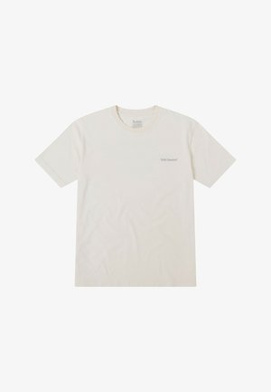 Camiseta corta de manga con cuello redondo en color crema, fabricada en algodón. Presenta un sutil logo en gris en la parte izquierda del pecho.