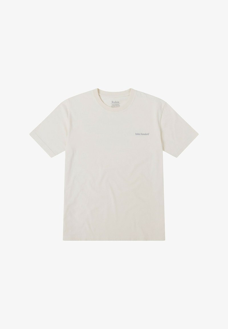 Camiseta corta de manga con cuello redondo en color crema, fabricada en algodón. Presenta un sutil logo en gris en la parte izquierda del pecho.