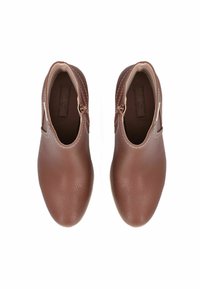 Scarpe di pelle marroni con finitura texture, punta rotonda e chiusura a cerniera sul lato. Accentuate da dettagli di cucitura crema.