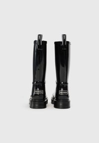 Bottes noires en caoutchouc étanches, montant jusqu'au genou, avec une finition brillante, dotées d'une languette à l'arrière, d'une semelle en caoutchouc épaisse et d'un logo sur le talon.