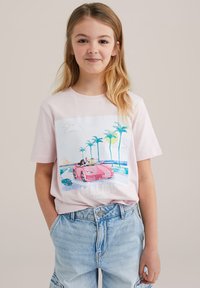 Rožinė medvilninė marškinė su spalvinga grafika, vaizduojančia du žmones rožiniame automobilyje, su palmėmis, saule ir užrašu "Pagaminta Malibū".
