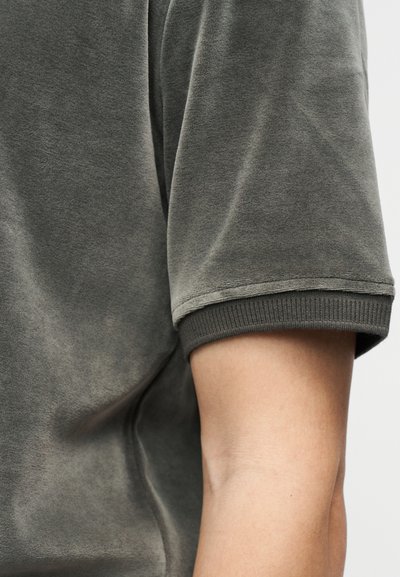 Κοντομάνικο T-shirt σκούρου γκρι χρώματος με απαλή υφή, διαθέτει στρογγυλή λαιμόκοψη και ριμπ μανσέτες. Κοντινό πλάνο δείχνει λεπτομέρειες στους ώμους και τα μανίκια.