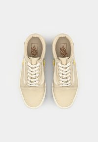 Beige canvas sneakers with white laces and side design, featuring yellow floral embroidery and a gum rubber sole.