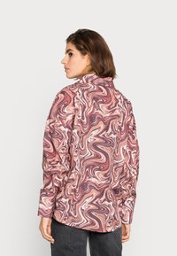 Camisa com padrão marmoreado em tons de rosa e creme, com colarinho e mangas longas, feita de um tecido leve e suave.
