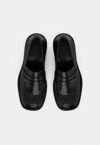 Pair of black leather square-toe slip-on loafers with strap detail, viewed from above on a white background.