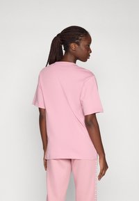 Rosa T-Shirt mit kurzen Ärmeln aus weicher Baumwolle, das ein einfaches Design und einen lässigen Schnitt aufweist. Der Stoff hat eine glatte Textur, ohne bemerkenswerte Muster.