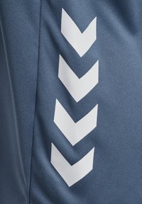 Niebieska tkanina o fakturowanej powierzchni z wyraźnymi białymi wzorami w kształcie jodełki, ułożonymi pionowo wzdłuż jednej strony.