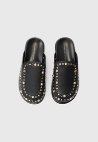 Melni slip-on klopi ar noapaļotu purngalu, rotāti ar zelta, sudraba un melnas metāla akcentiem gar malām. Gluda teksturēta augšējā materiāla virsma.