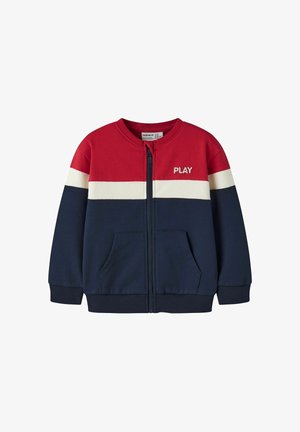 Børnejakke med lynlås med rød top, hvid midterstribe, mørkeblå bund, forlommer og ordet "PLAY" på brystet.