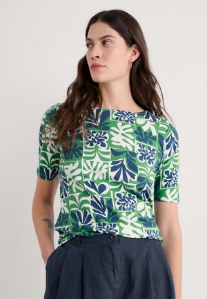 T-shirt a maniche corte con stampa di foglie tropicali in verde, blu e bianco su tessuto di cotone elasticizzato. Collo rotondo e vestibilità comoda.