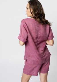 Roze linnen overhemd met korte mouwen en opgerolde manchetten, met bijpassende shorts. Heeft een losse fit en zijsplitten, en toont een gestructureerde stof.