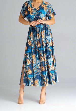 Frau trägt ein midilanges Kleid mit blau-orange-schwarzem Marmormuster, kurzen Ärmeln, V-Ausschnitt, Seitenschlitz und beigen High-Heel-Sandalen.