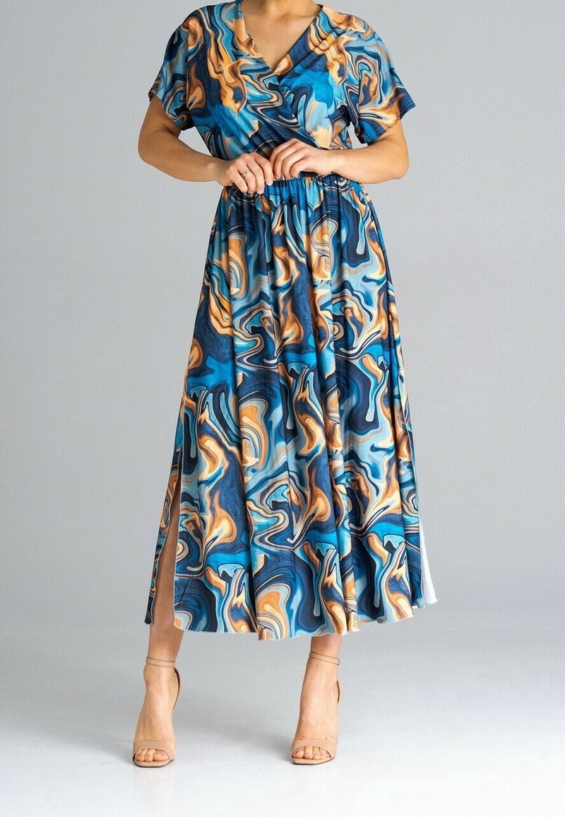 Femme portant une robe midi à motif marbré bleu, orange et noir avec manches courtes, col en V, fente latérale et sandales à talons hauts beiges.