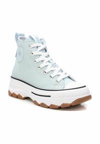 Scarpe alte blu chiaro con suola in gomma, lacci bianchi e una striscia di accentuazione nera. Presentano un logo circolare sul lato e una punta strutturata.
