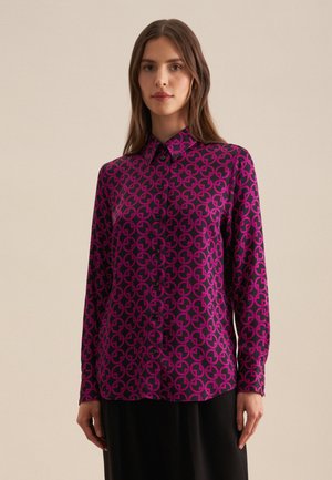 Lila- und schwarze Hemdjacke mit geometrischem Muster. Verfügt über einen Kragen und lange Ärmel und besteht aus glattem, leichtem Material.