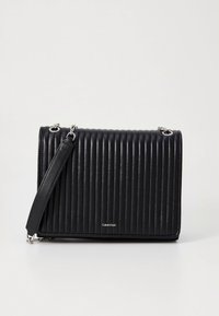 Svart skinnveske med vertikal ribbet tekstur, sølvdetaljer, justerbar skulderrem, med en logo på forsiden.