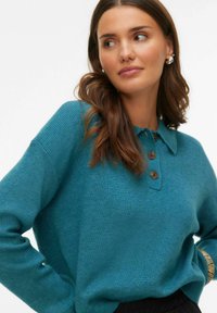 Morski sweter z dzianiny z kołnierzykiem typu polo, drewnianymi guzikami, ściągaczami na mankietach i luźnym krojem. Gładka faktura i subtelny połysk.