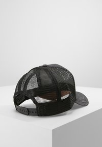 Cappellino da camionista nero con retro in rete, visiera piatta e chiusura regolabile con snap. Presenta un tessuto testurizzato con un motivo sottile sulla visiera.