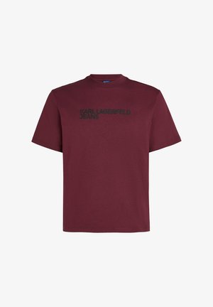 Camiseta de manga corta burdeos con cuello redondo que presenta el texto negro "KARL LAGERFELD JEANS" en el pecho. Fabricada en tela de algodón.