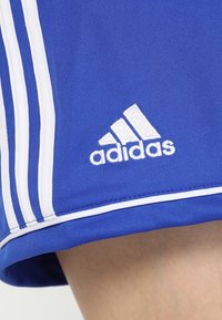 Pantalones cortos deportivos azules con detalles blancos, que presentan tres franjas blancas a lo largo del lateral y un logo de Adidas bordado en el dobladillo.