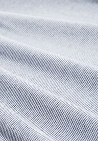Tela de algodón con un fino patrón de rayas en azul claro y blanco. Textura suave, se pliega en caídas, resaltando las fibras entrelazadas.