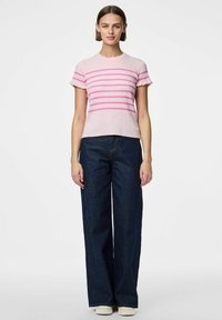 Svijetloružičasti rebrasti pleteni top s horizontalnim tamnoružastim prugama, kratkim volančićima; uparen s širokim tamnim trapericama i bijelim tenisicama.