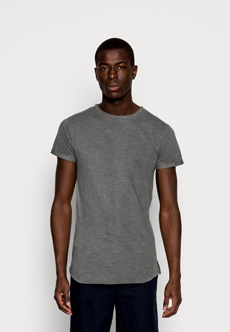 Grå kortærmet t-shirt lavet af blødt, struktureret stof med rund hals; har en lidt længere kant bagpå.