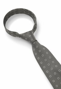 Grijze stropdas met een gestructureerd oppervlak, met een patroon van kleine witte vierkantjes. De stropdas is opvallend geknoopt aan de bovenkant.