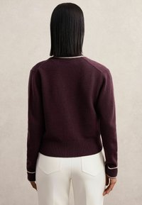Pulover tricotat burgundy cu tiv și manșete rib și detalii albe. Vederea din spate evidențiază un design ajustat.