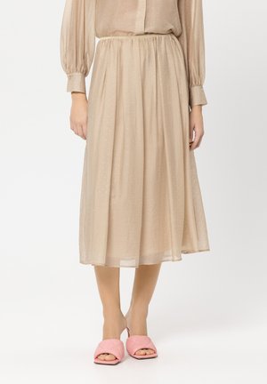 Beige, plissierter Midirock aus leichtem Stoff mit subtilen Glitzerakzenten, kombiniert mit pinken, gesteppten Slip-On-Sandalen.