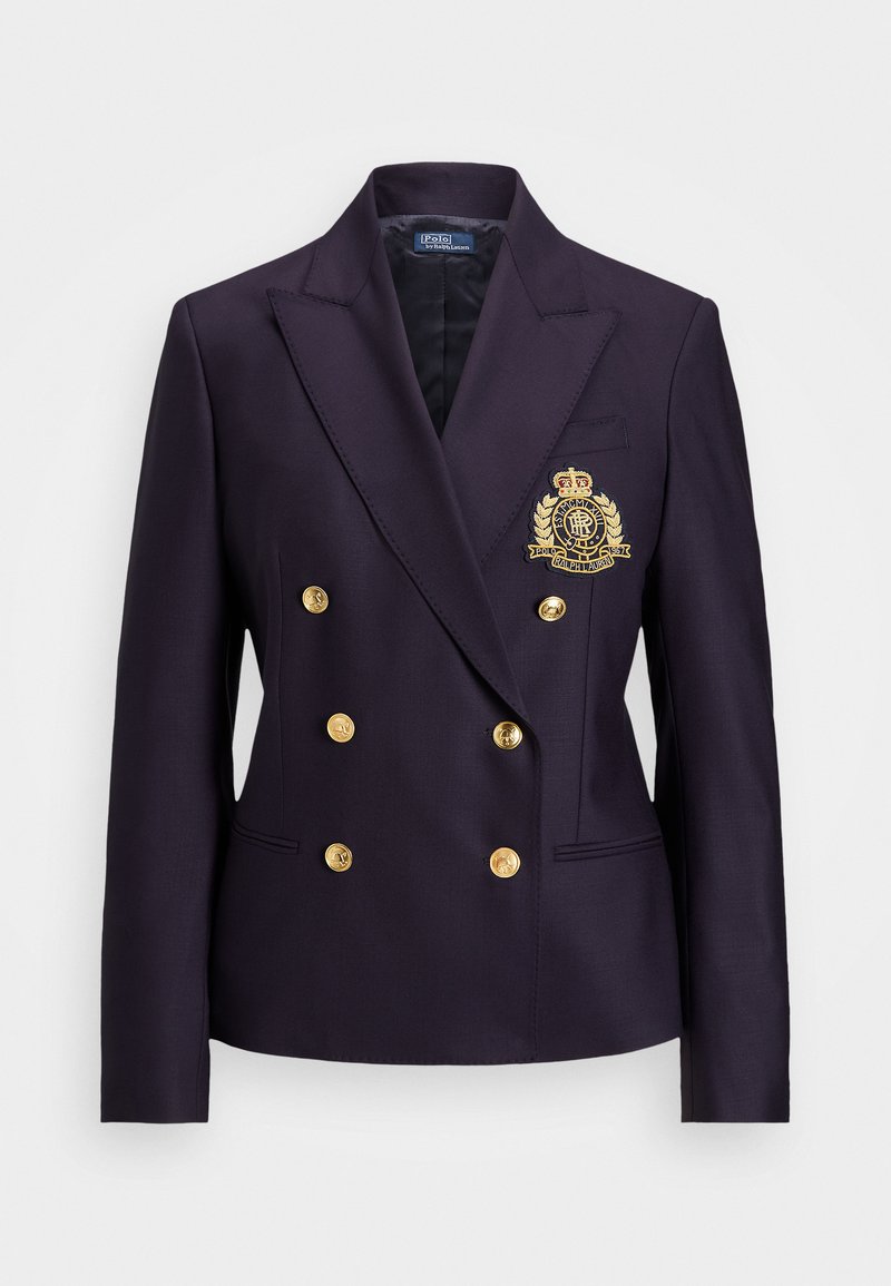 Marineblauwe dubbelrijige blazer met gouden knopen, gekartelde revers en geborduurd embleem op de linkerborst. Soepele stoftextuur.