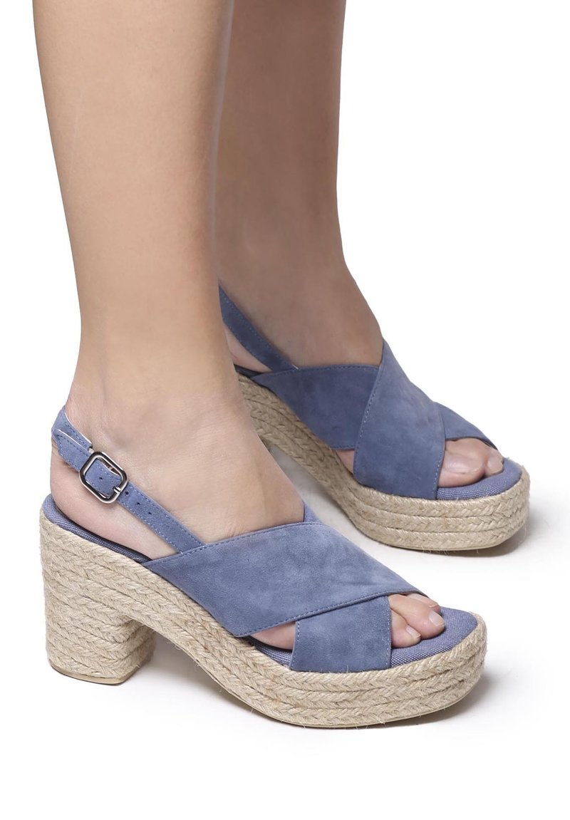 Plave suede wedge sandale s preklopljenim trakama, otvorenim prstima i tkanim jutenim platformom. Imaju podesivu trakicu za gležanj sa srebrnom kopčom.