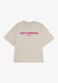 Beige Oversized-T-Shirt aus Baumwolle mit kurzen Ärmeln. Mit auffälligem pinken Text "SCHLAF IST ÜBERBEWERTET" und "PEGADOR" darunter.